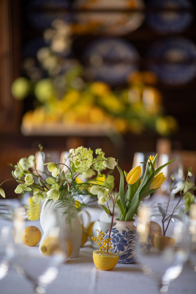 Centro de mesa decorado en tonos amarillos con limones, tulipanes y helleborus